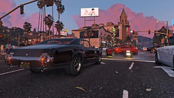 Carros num cruzamento de Vinewood ao entardecer, com palmeiras e letreiros ao fundo